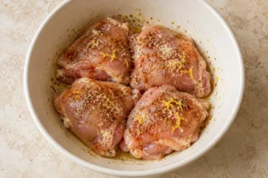 Raw chicken thighs coated in lemon zest, oil and paprika