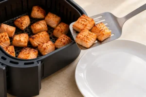 Lifting cooked salmon bites onto a clean plate